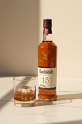 Glenfiddich 15 Años 500ml con vaso tumbler y hielo sobre mármol crema