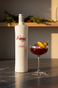 Vermú Petroni Tinto 500ml con copa coupe, naranja y aceitunas sobre mármol oscuro